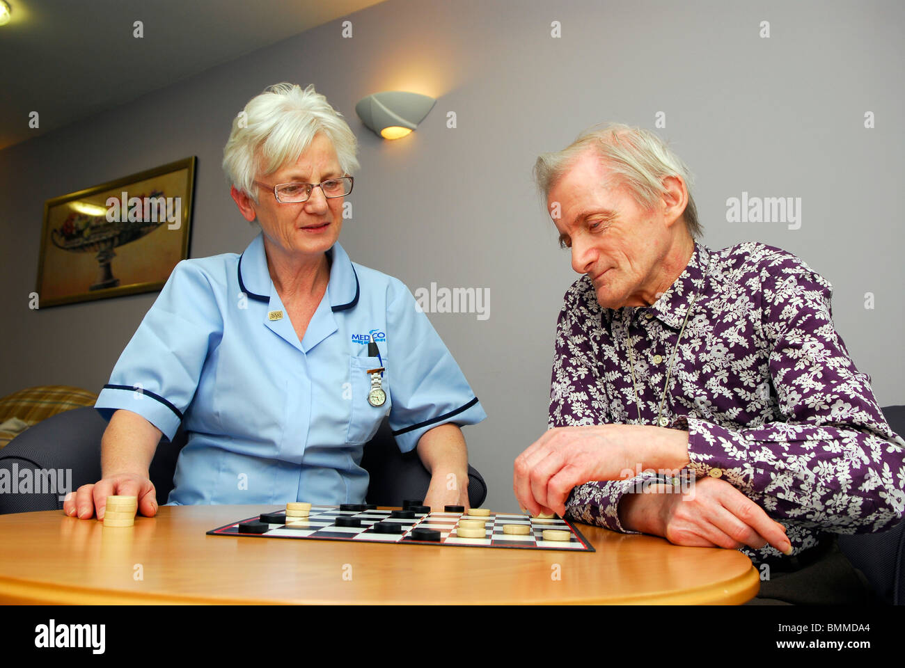 Healthcare worker playing a board game with an elderly resident at an old people's home, Wirral, UK. Stock Photo