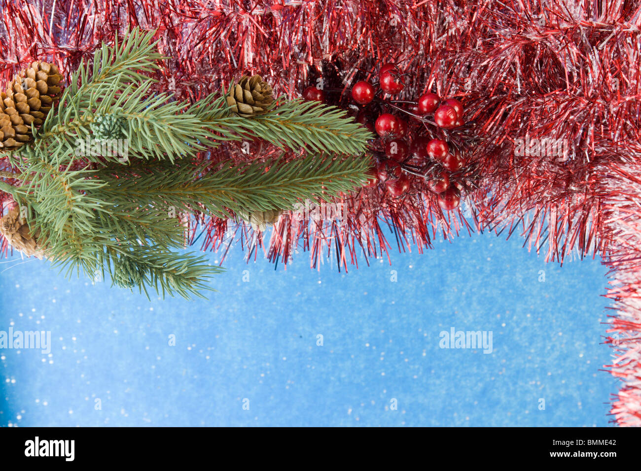 red and white Christmas tinsel garland corner frame with fir branch, holly berries and copyspace Stock Photo