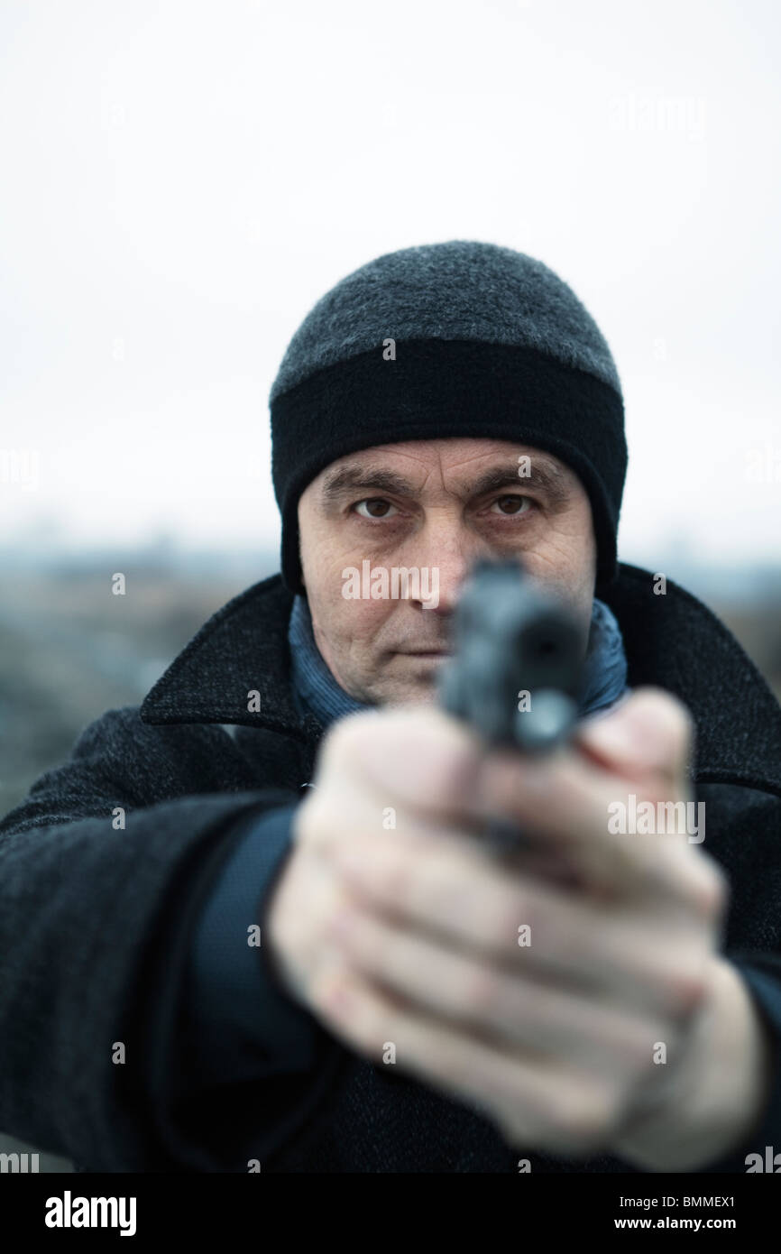 Man pointing a loaded handgun Stock Photo