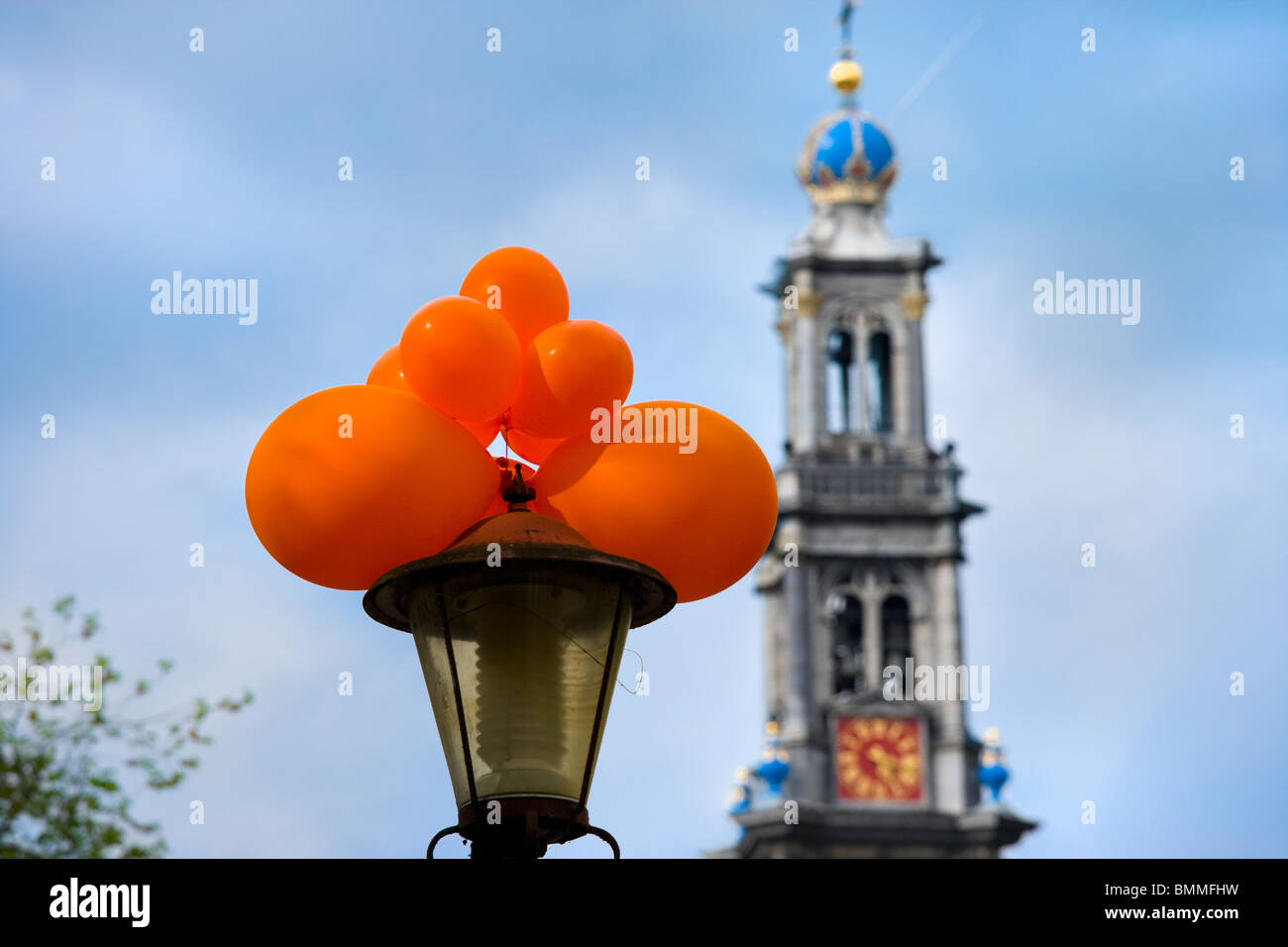 Amsterdam Westertoren, West Western Church Tower, icon for the city, with street light and festive orange balloons. On Kings day Stock Photo