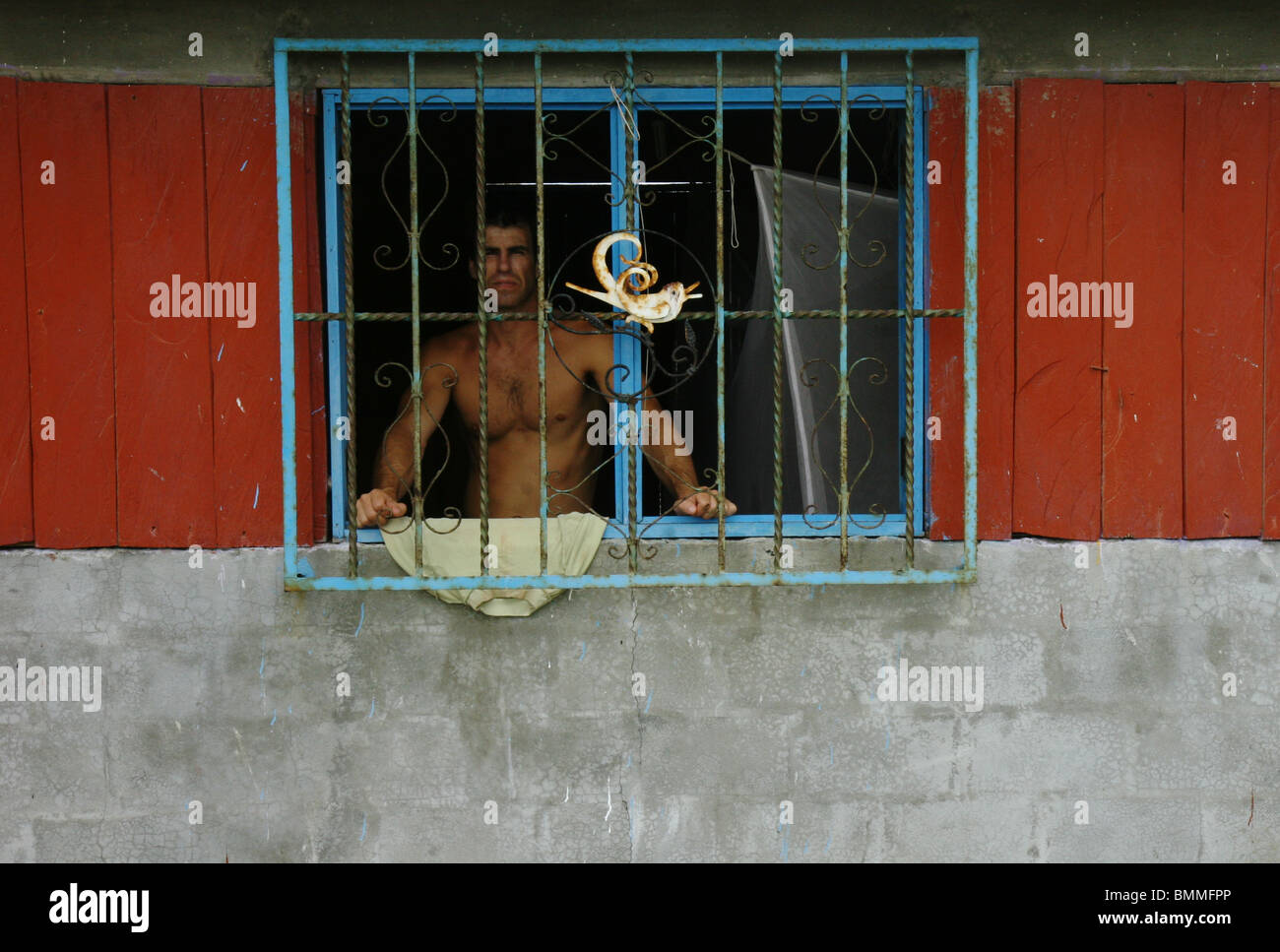 Man stares out of his barred window Stock Photo