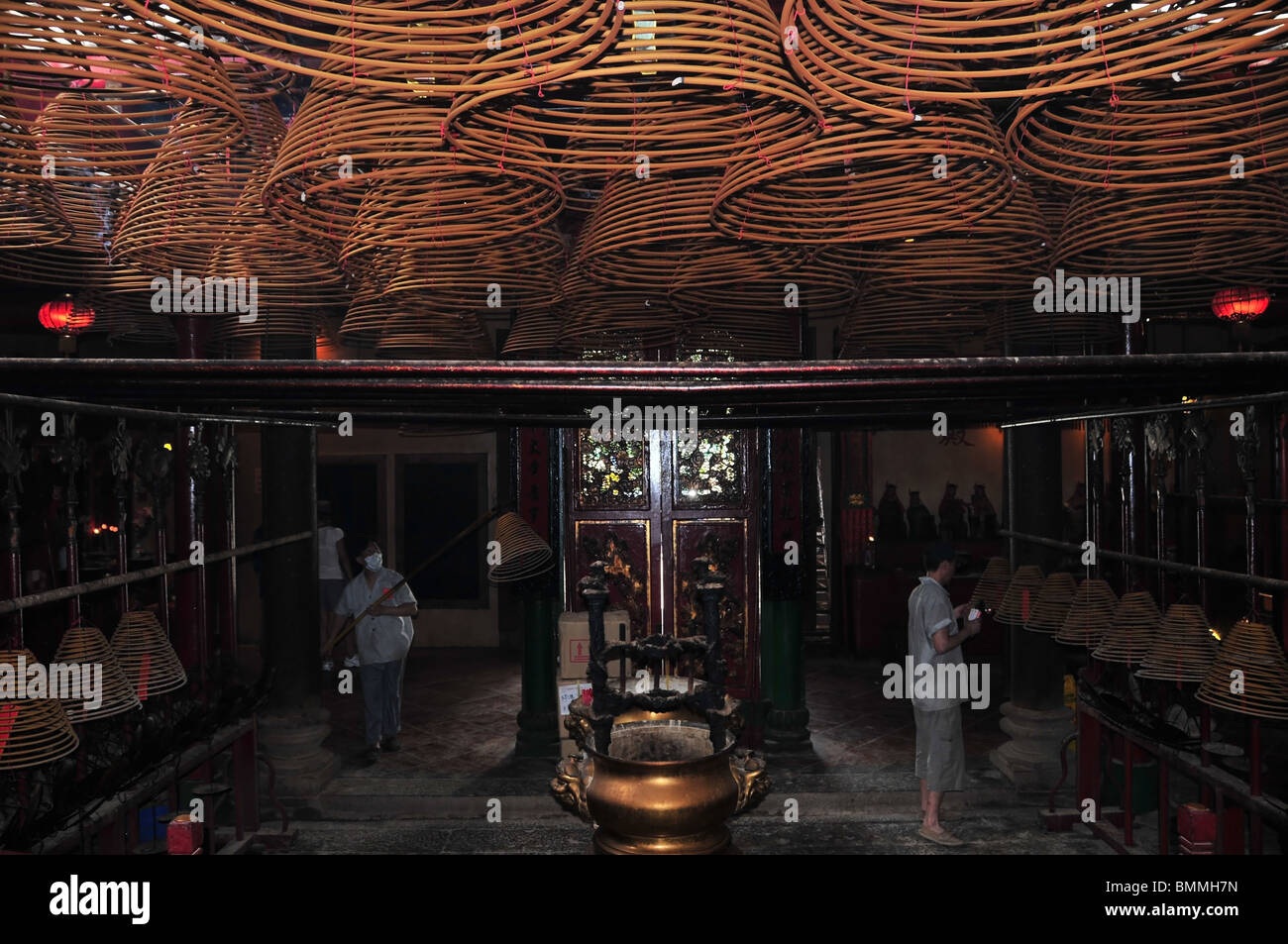 Attendants with blow torch and wooden pole lighting and lifting incense