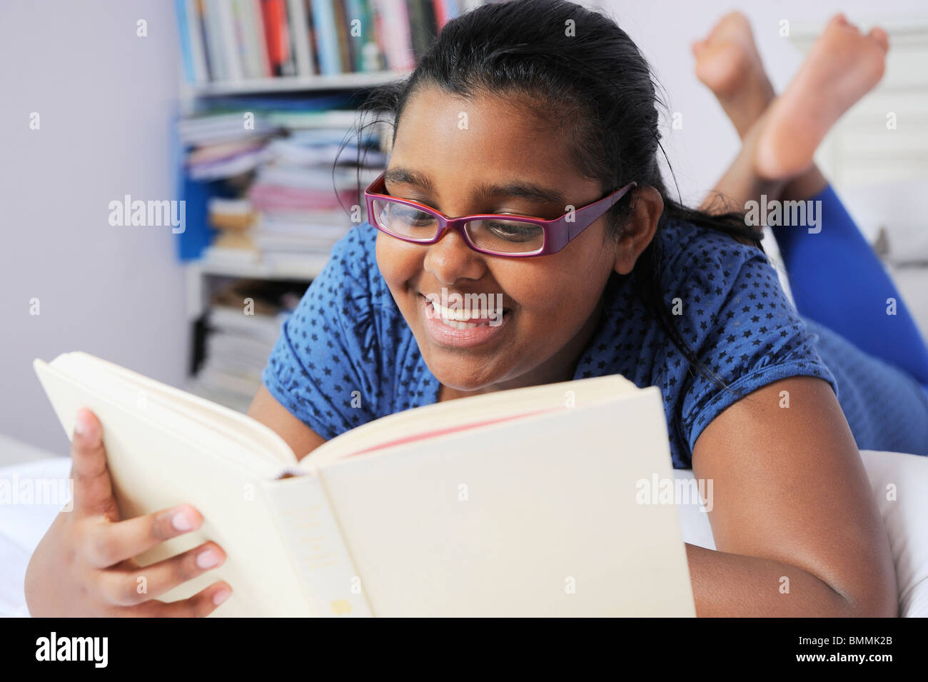Girl lying on bed, reading book, Cape Town, Western Cape Province, South Africa Stock Photo