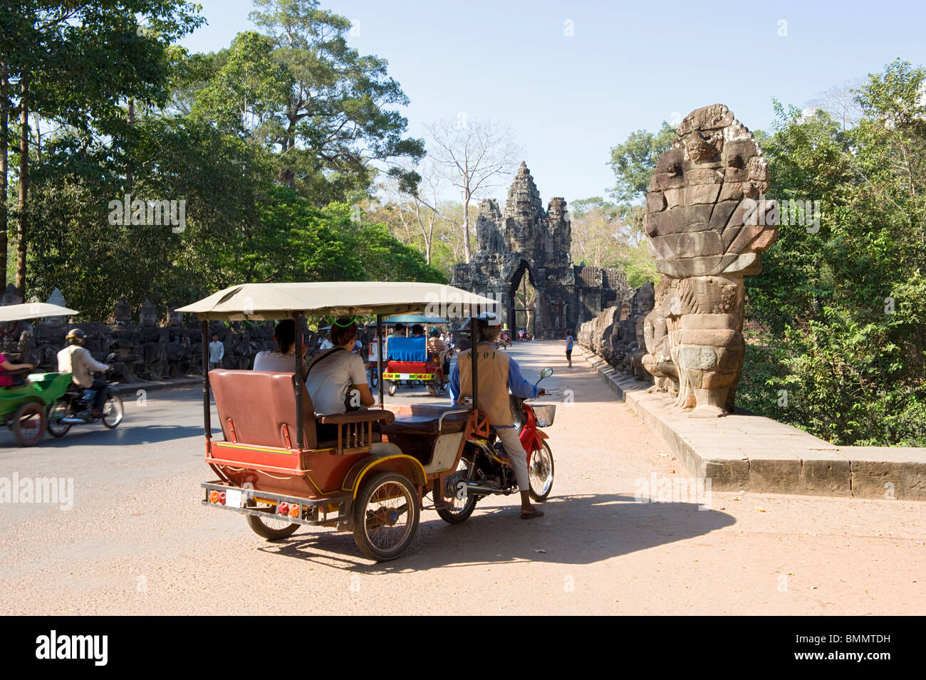 Motorcycle tuk tuks by the naga statues and Victory gate near South entrance to Angkor Thom Stock Photo