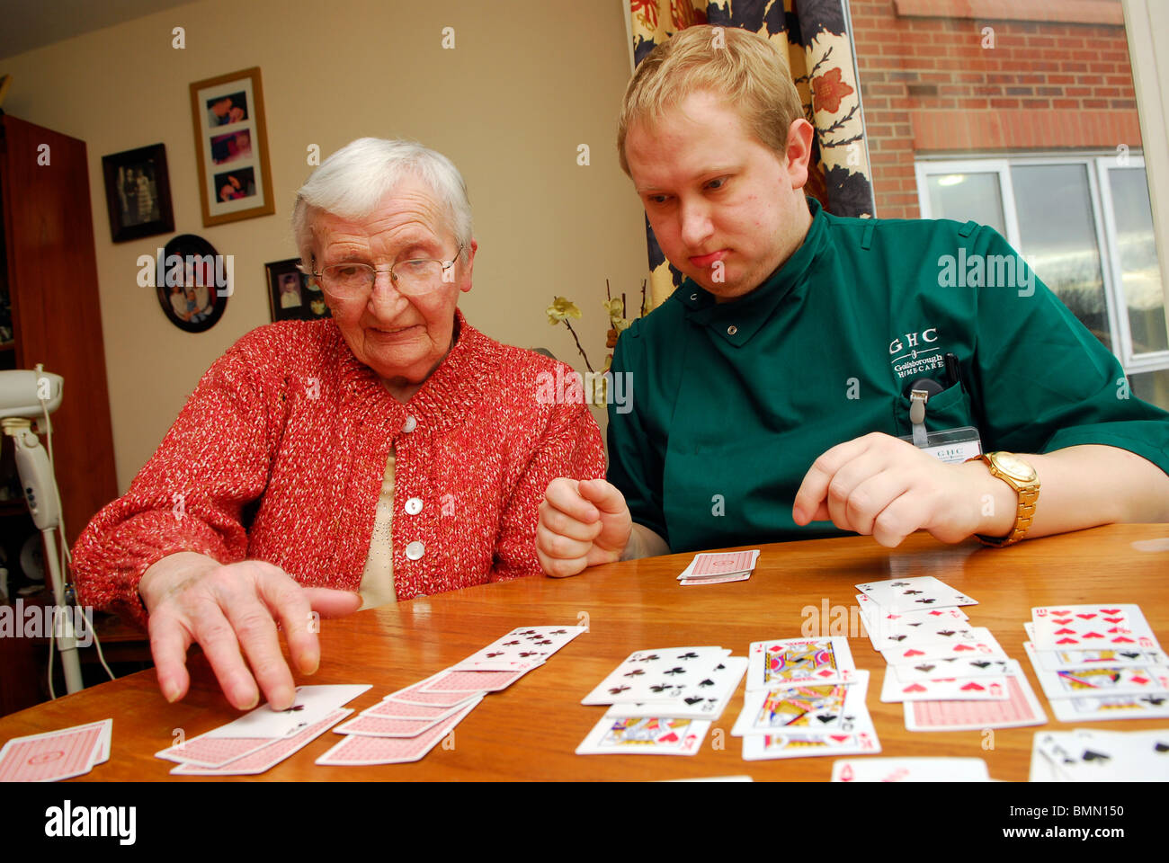 Care worker playing cards with an elderly lady in residential care home, Wirral, UK. Stock Photo