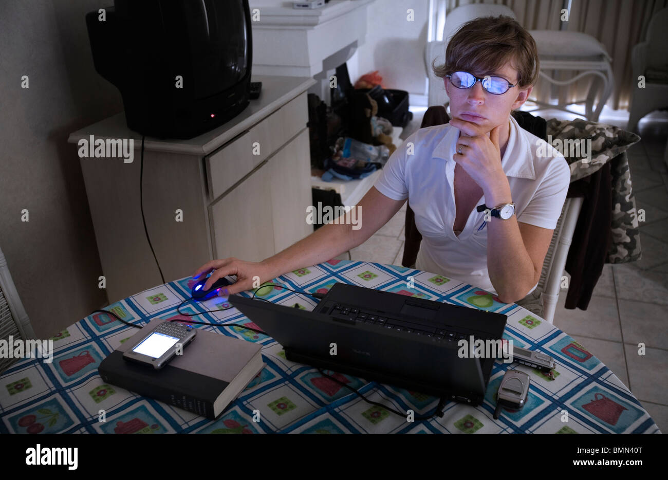 A young woman working with a computer with bluish screen reflections on ...