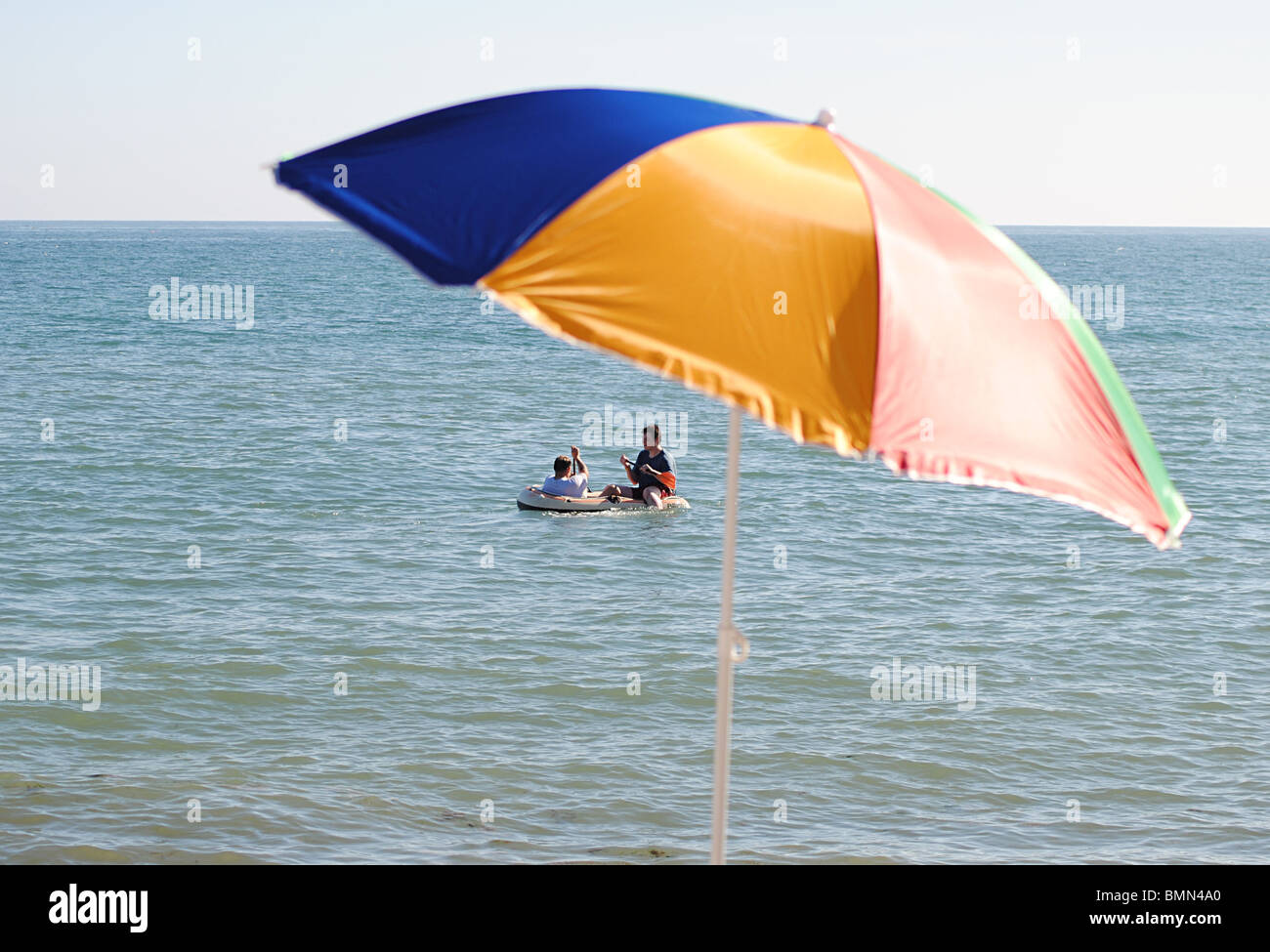Boys paddle in an inflatable boat off Charmouth Beach, England Stock Photo