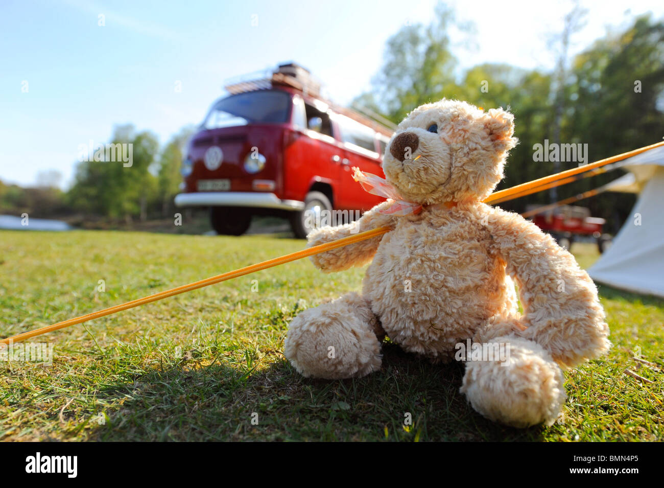 A teddy bear enjoying a camping holiday in a bright red classic VW campervan. Stock Photo