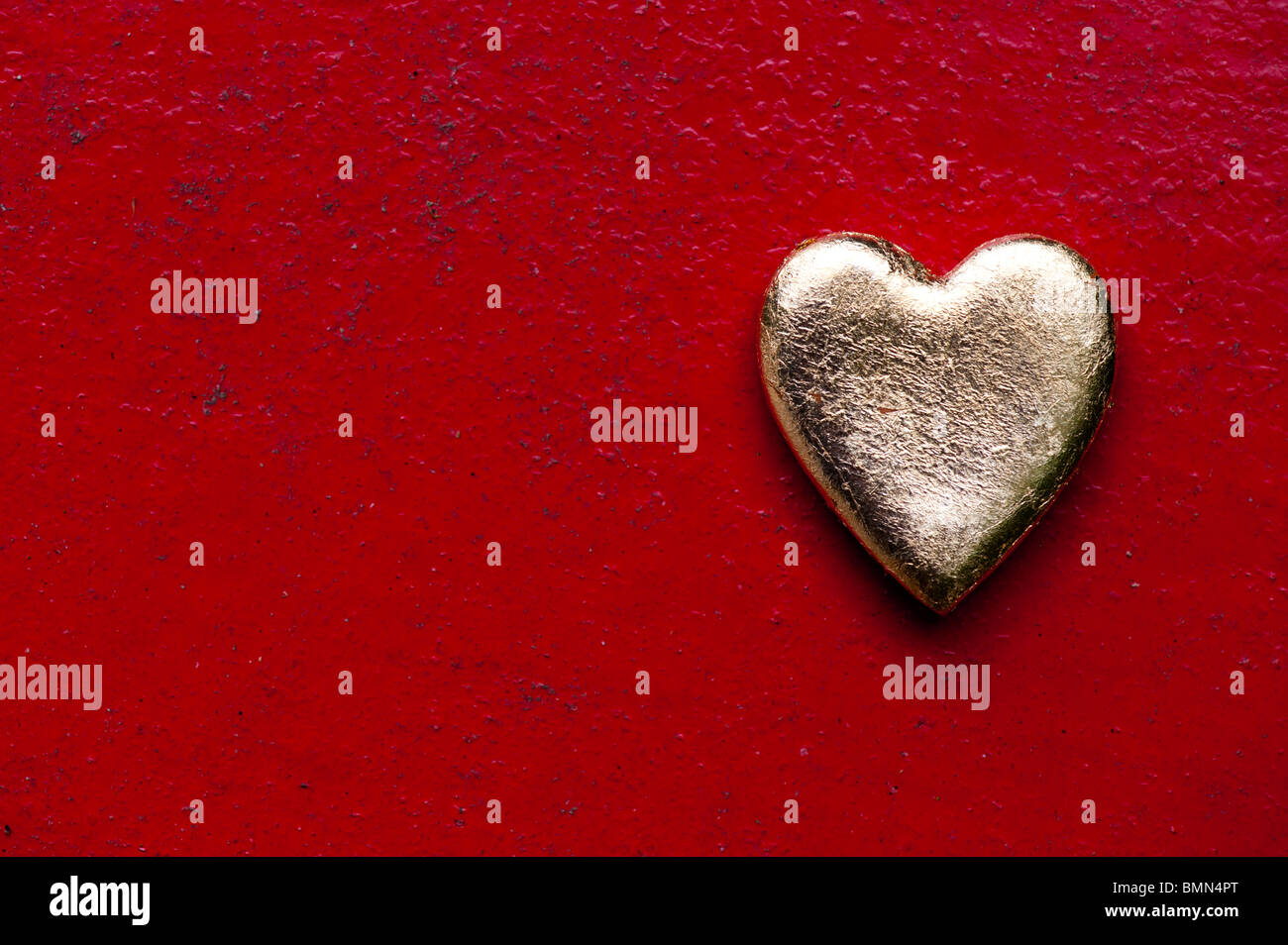 Gold heart shape against red texture metal painted background Stock Photo