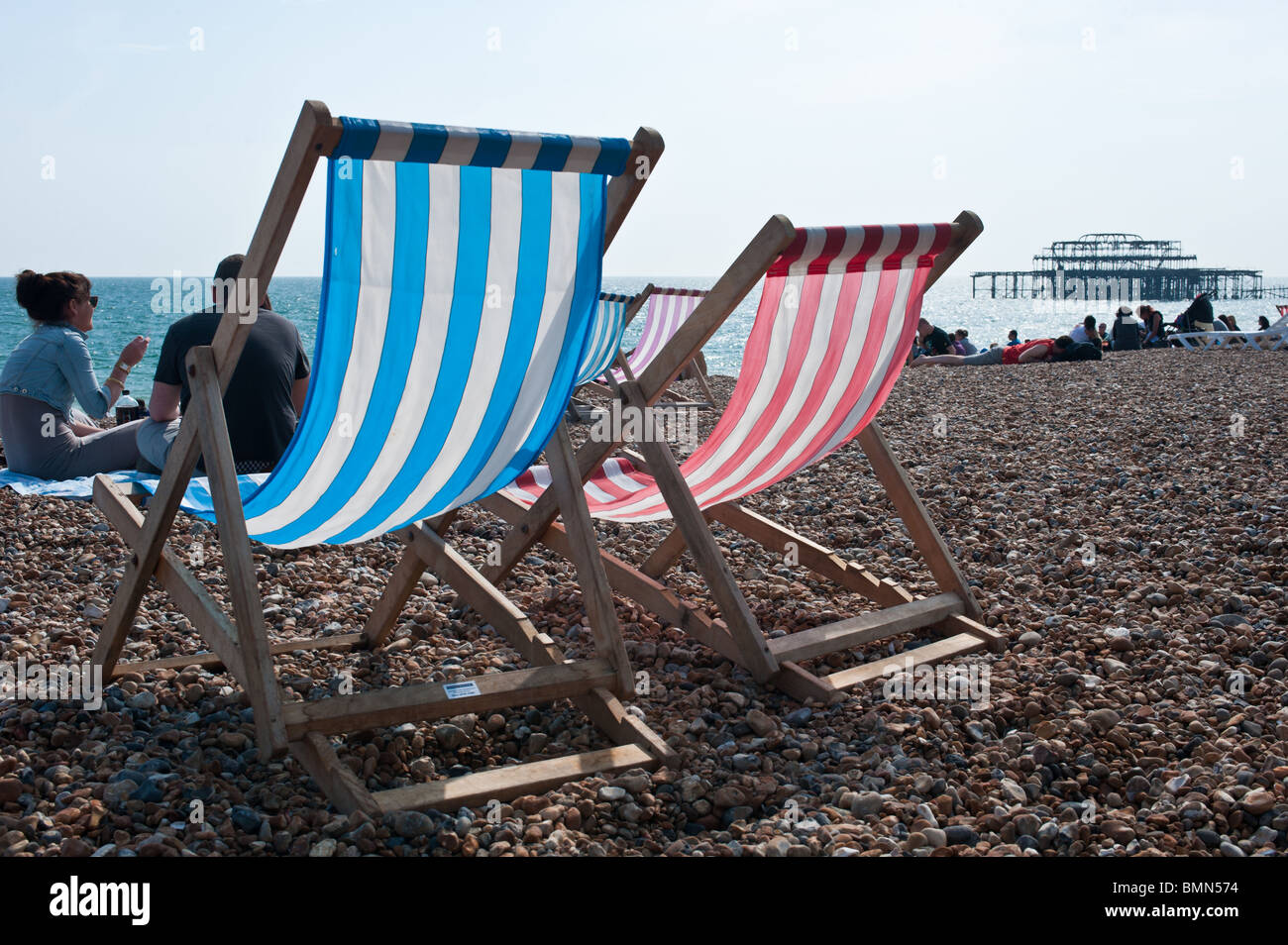 Deck chairs and crowds on a sunny Brighton beach with the west pier in