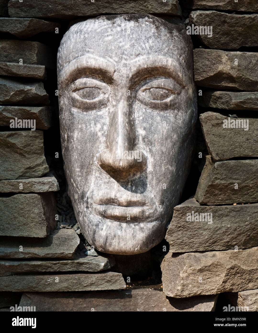 A sculpted face peers out of a cairn at the North Carolina Botanical Garden in Chapel Hill. Stock Photo
