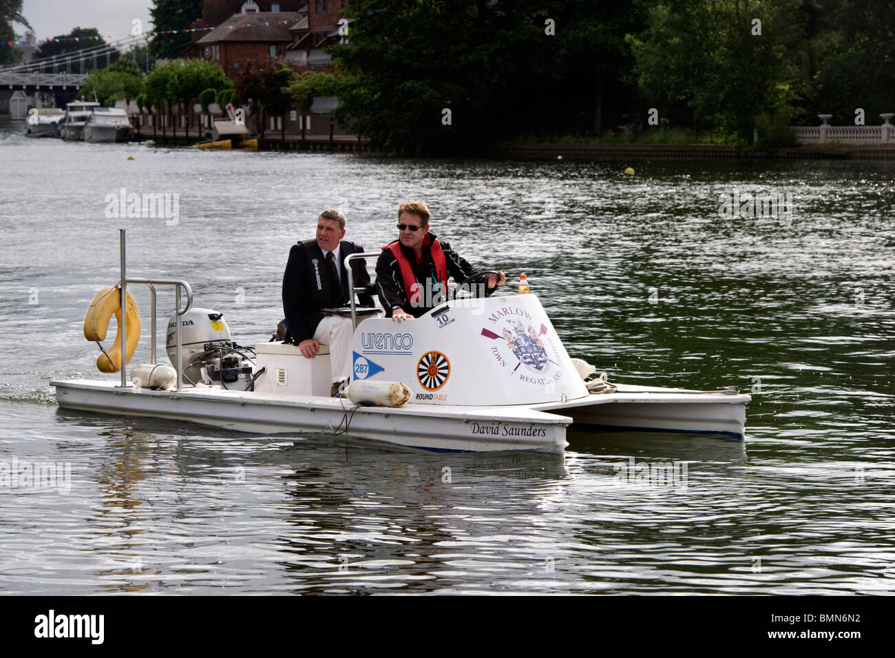 Two umpires at Marlow regatta on a motor boat moving upstream on the River Thames Stock Photo