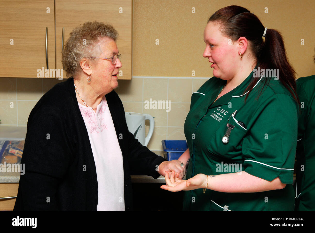 Healthcare worker interacting with elderly resident at an old people's home, Wirral, UK Stock Photo