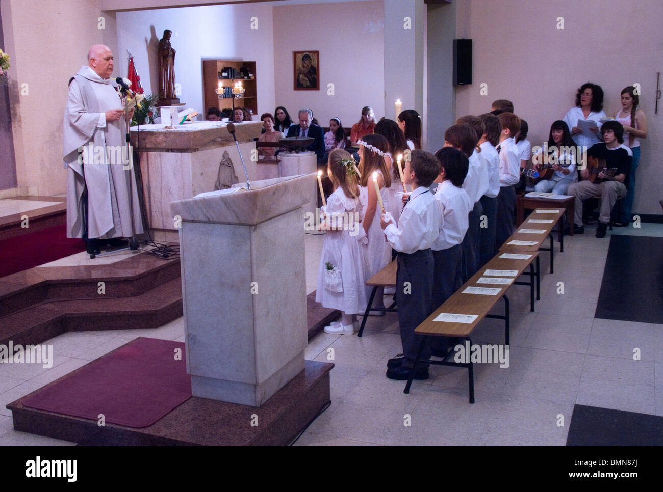 priest giving speech and children standing and holding candlelight Stock Photo
