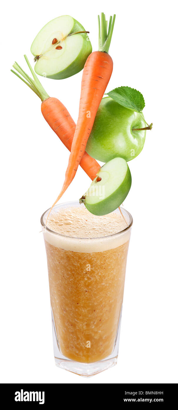 Slices of apple and carrot falling into a glass of fresh juice Stock Photo