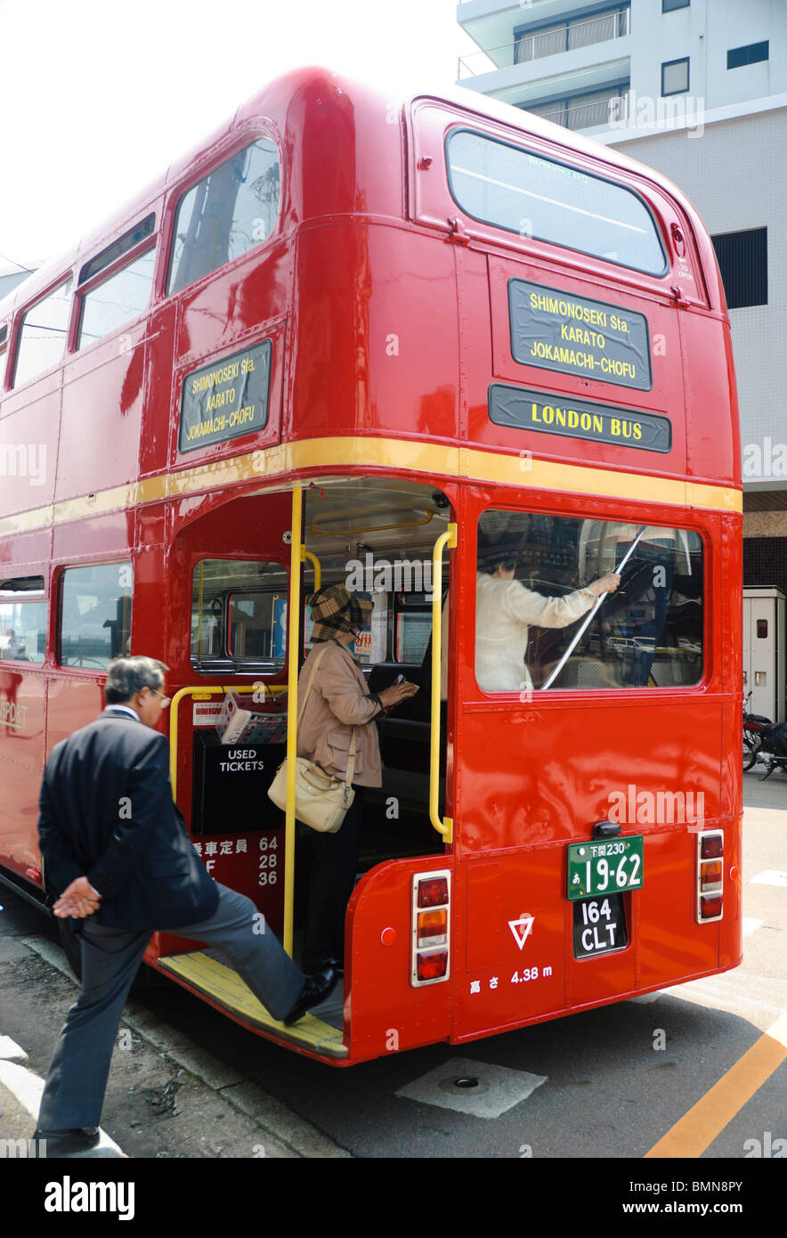 Red London bus with Japanese tourists; passengers boarding through rear entrance; Routemaster double decker bus. Please click for details. Stock Photo