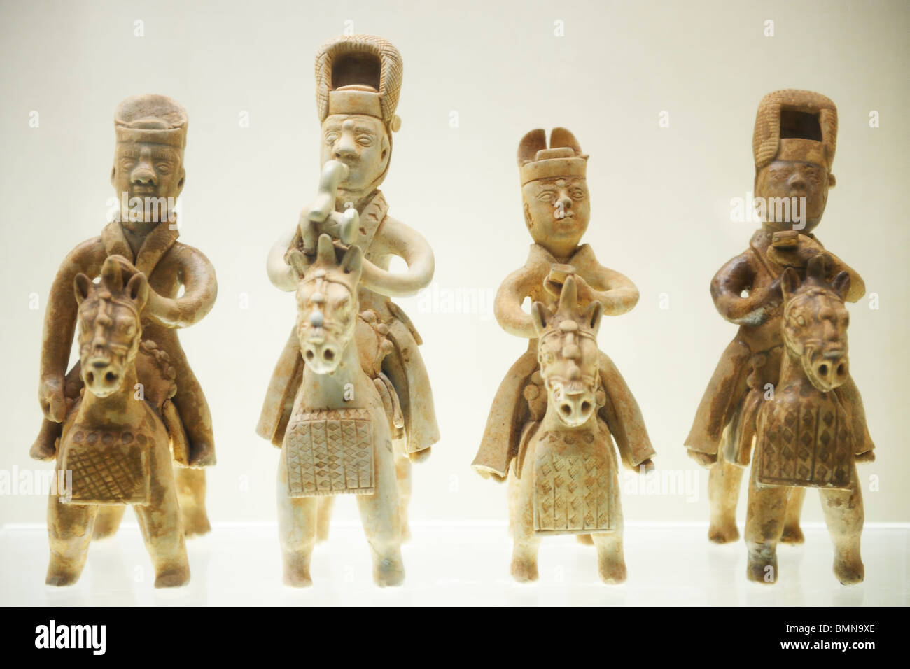 Four bronze statues of men riding horses wearing ancient Chinese military armor and tall hats. Stock Photo