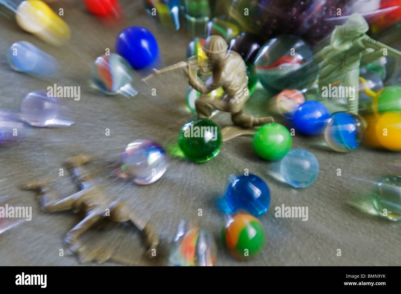 A battle takes place with green plastic action figure toy soldiers and marbles. Stock Photo