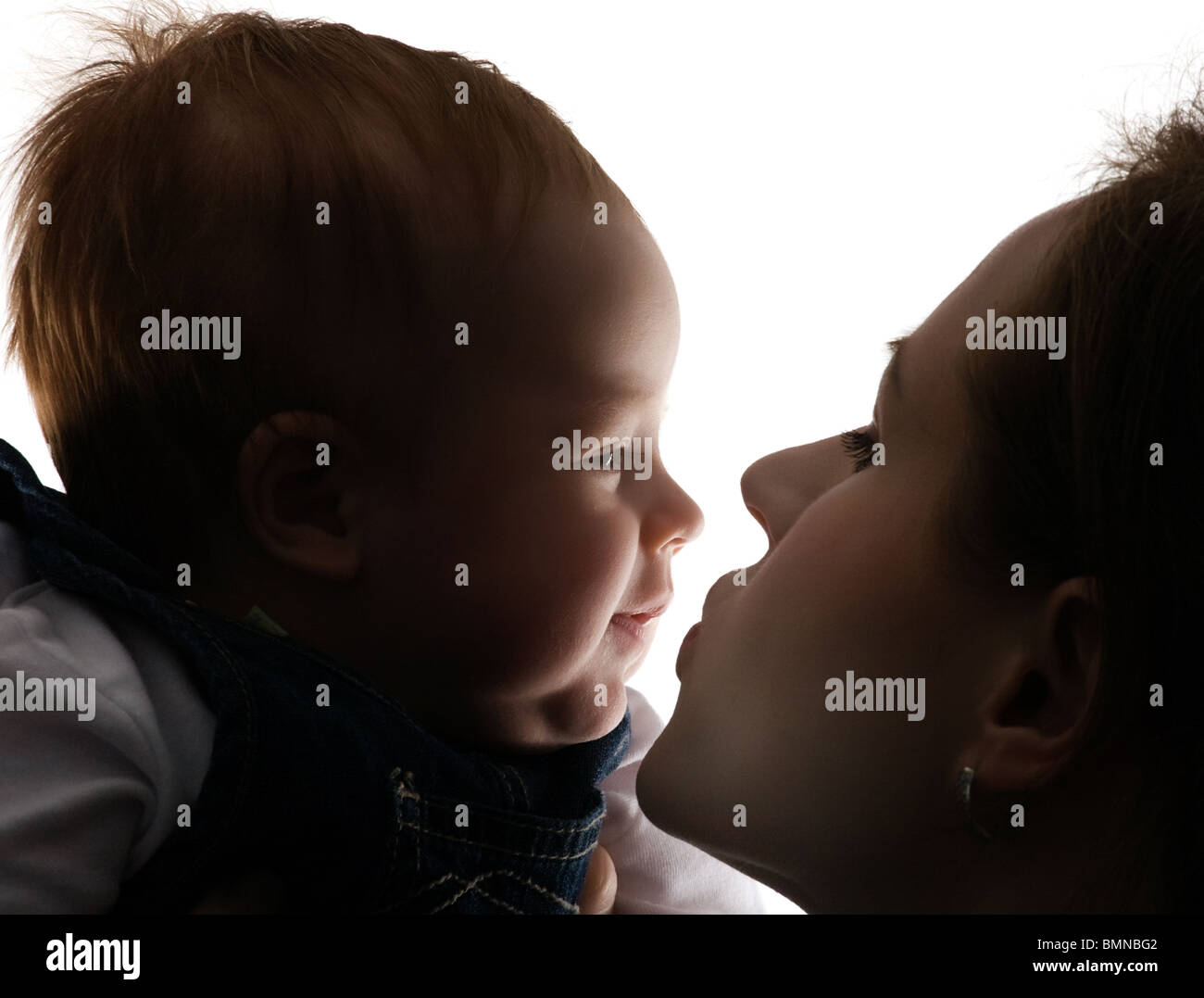Portrait in a profile of mum and the child, mum kisses the kid, isolated on white Stock Photo