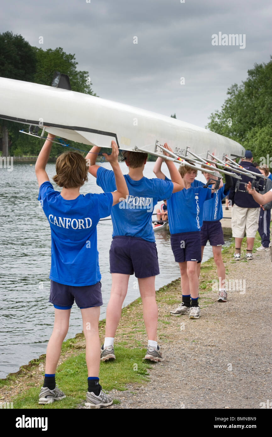Young people, rowers, competitors carrying a skiff at Marlow Regatta on the banks of the River Thames Stock Photo