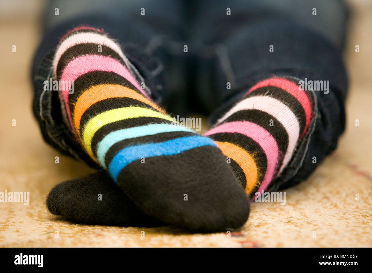 Teenager lies on floor with feet in view. Stock Photo