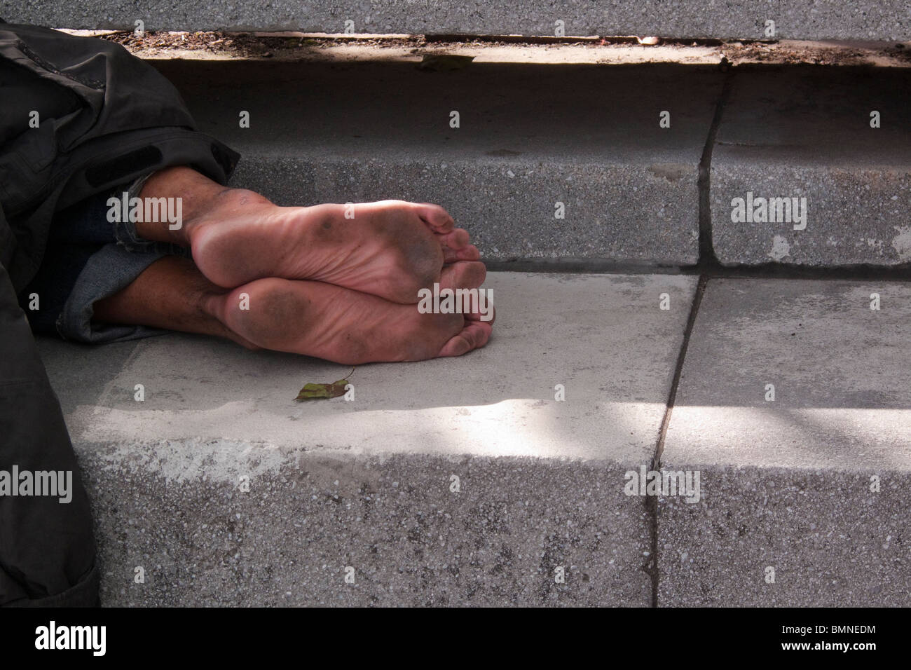 Homeless man asleep on a concrete park bench Stock Photo - Alamy