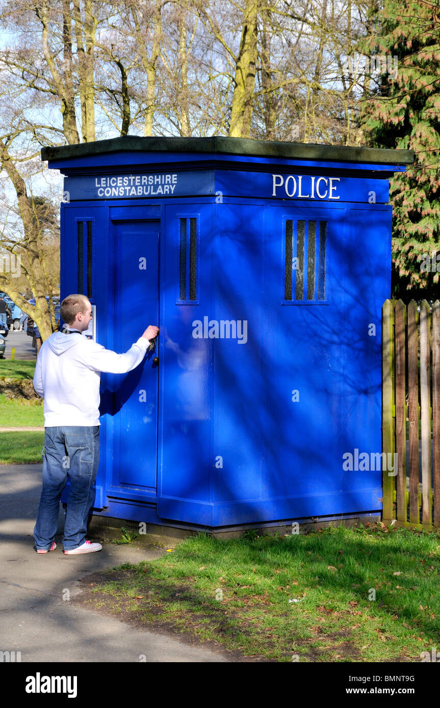 Man unlocking a blue police telephone box in England. Stock Photo