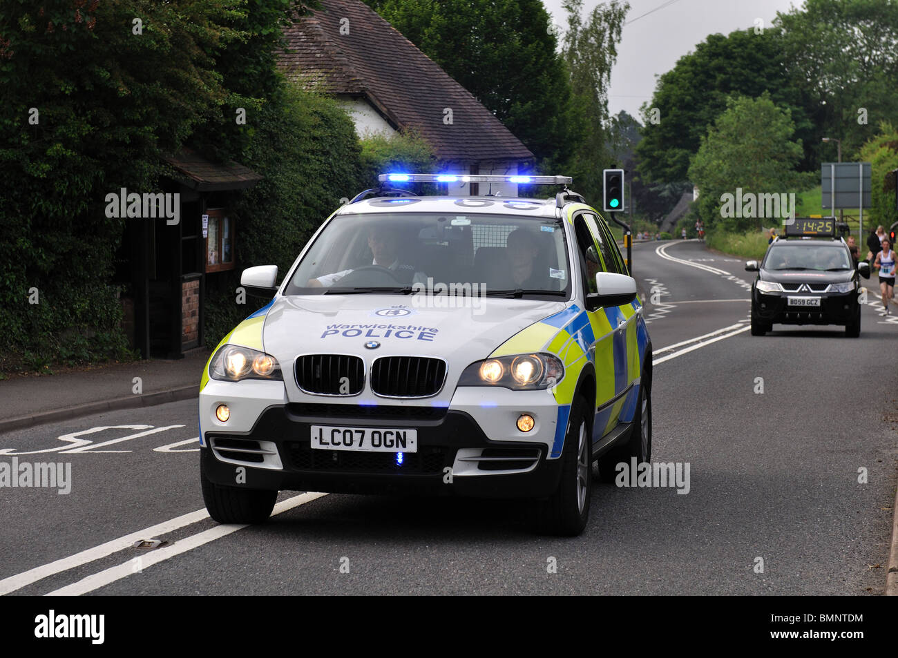 Police car leading Two Castles 10K road race at Leek Wootton, Warwickshire, UK Stock Photo