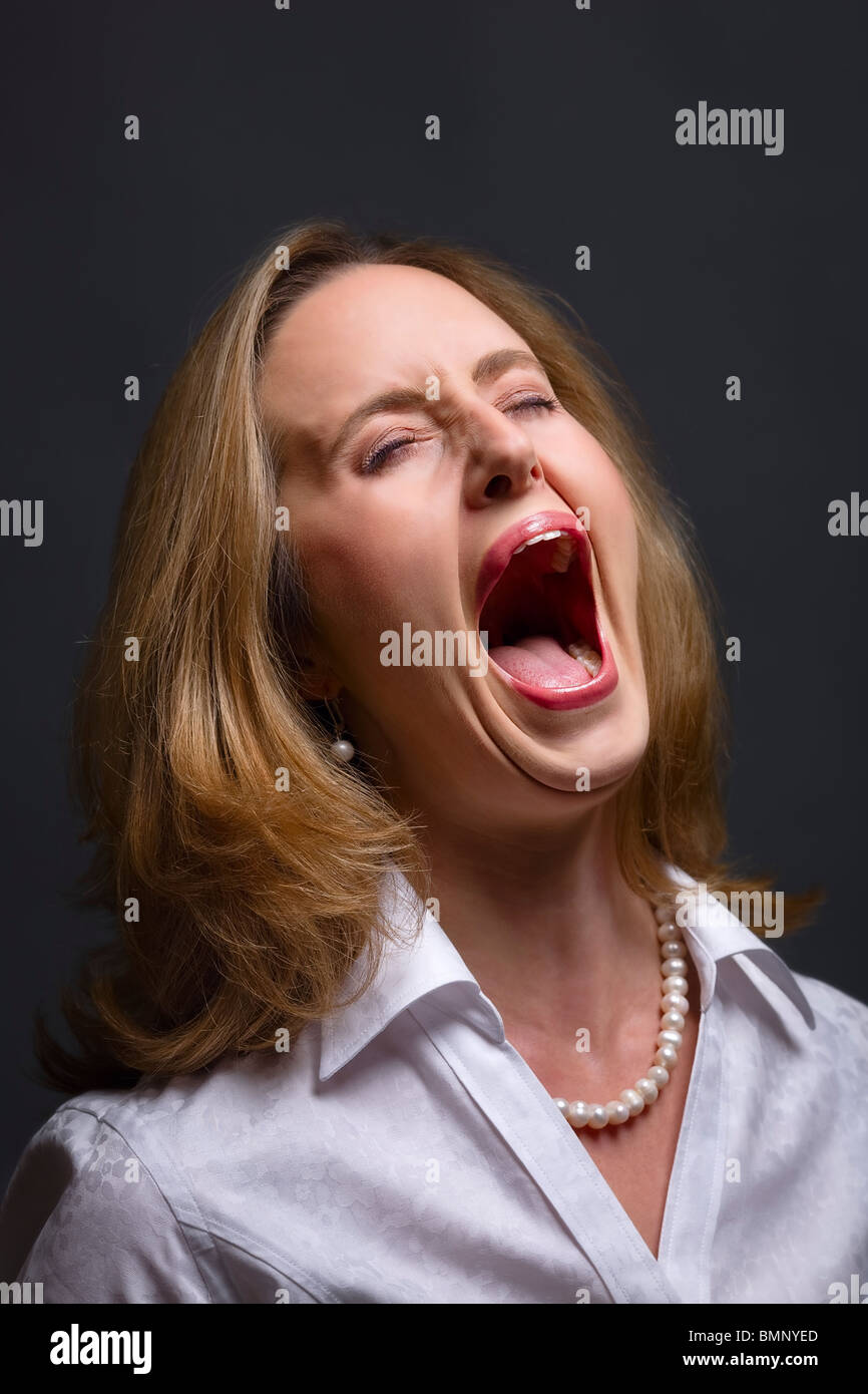 Portrait of woman with open mouth as if shouting, singing or screaming in pain Stock Photo
