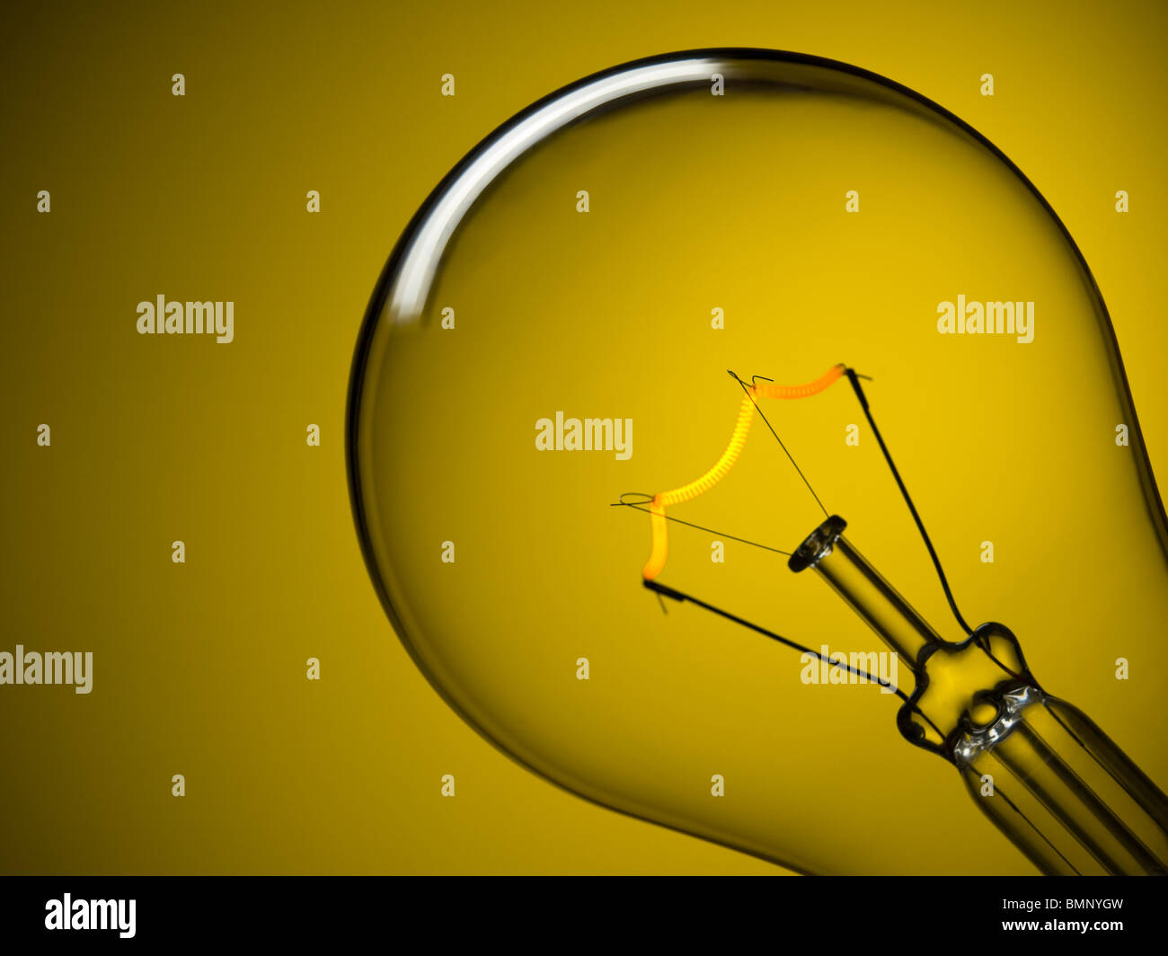Close up on a turned on light bulb over a yellow background. Stock Photo