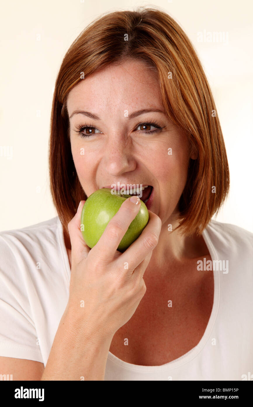 WOMAN EATING A GREEN APPLE Stock Photo