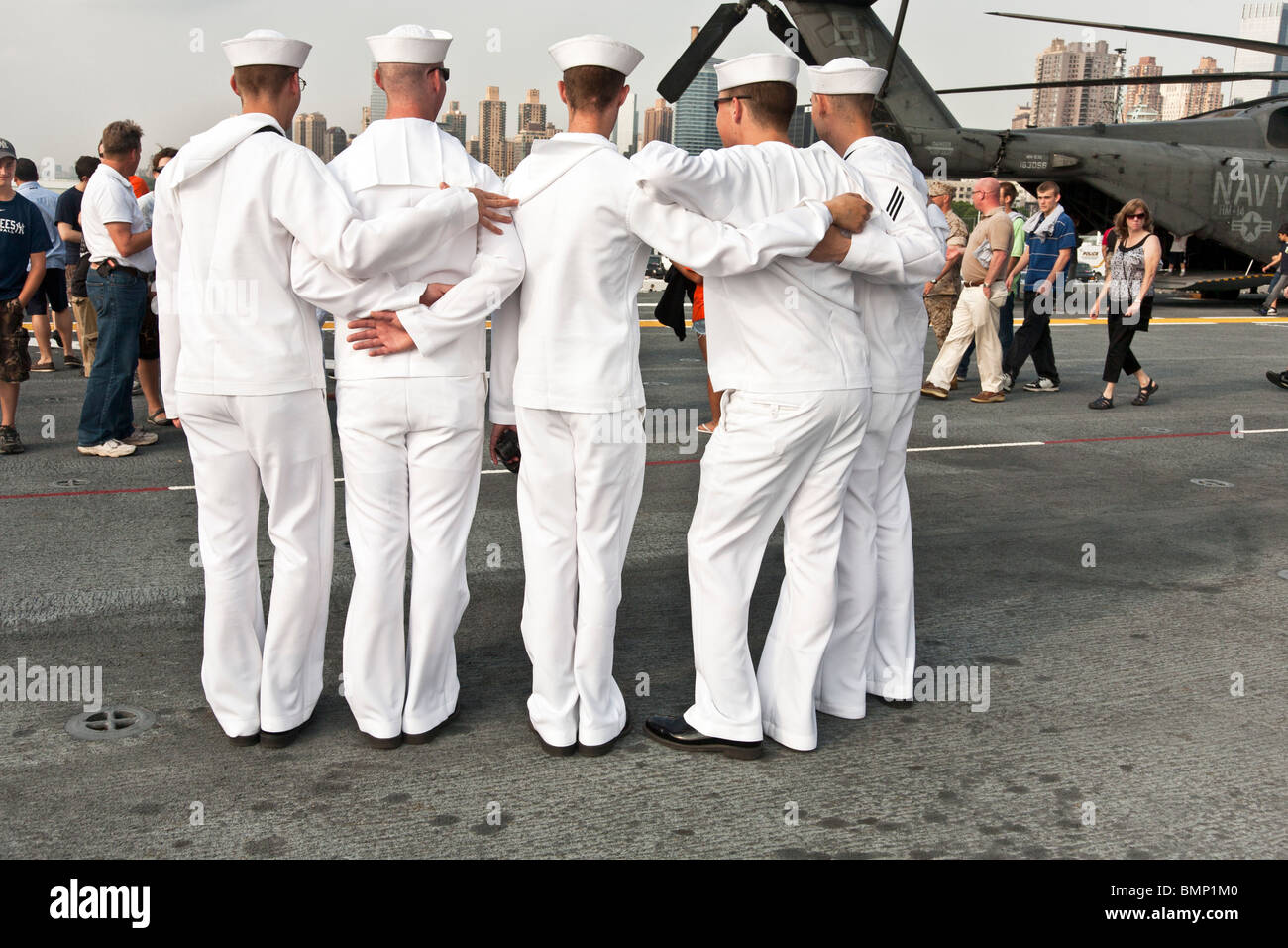 five young sailors in dress whites pose for visitors to Flight deck of USS Iwo Jima during fleet week in New York City Stock Photo
