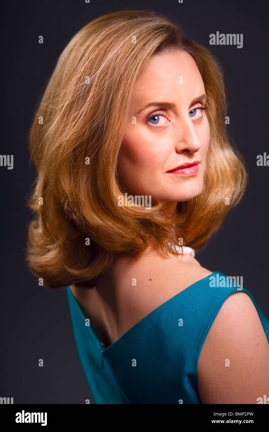 Sophisticated blue-eyed blonde woman on dark background Stock Photo