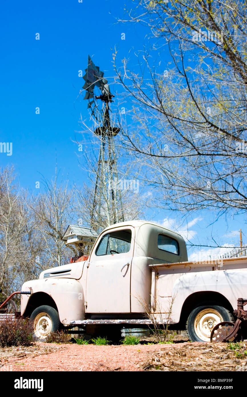 Antique Ford truck at the base of an old fashioned windmill pump Stock Photo