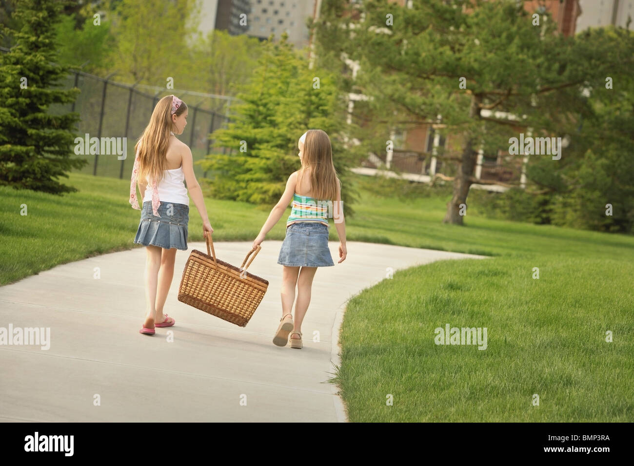 Edmonton, Alberta, Canada; Two Girls Carrying A Picnic Basket Down The