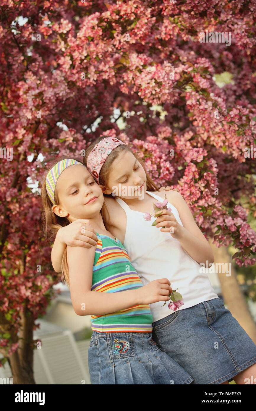 Edmonton, Alberta, Canada; Two Girls Holding Flowers Under A Blossoming