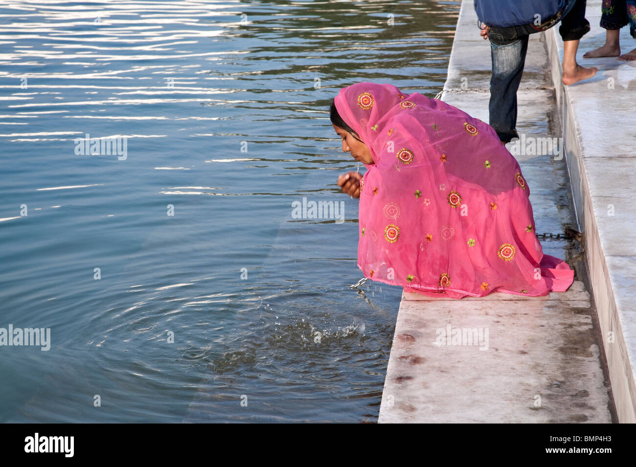 Woman drinking water from the sacred pool. The Golden Temple. Amritsar. Punjab. India Stock Photo