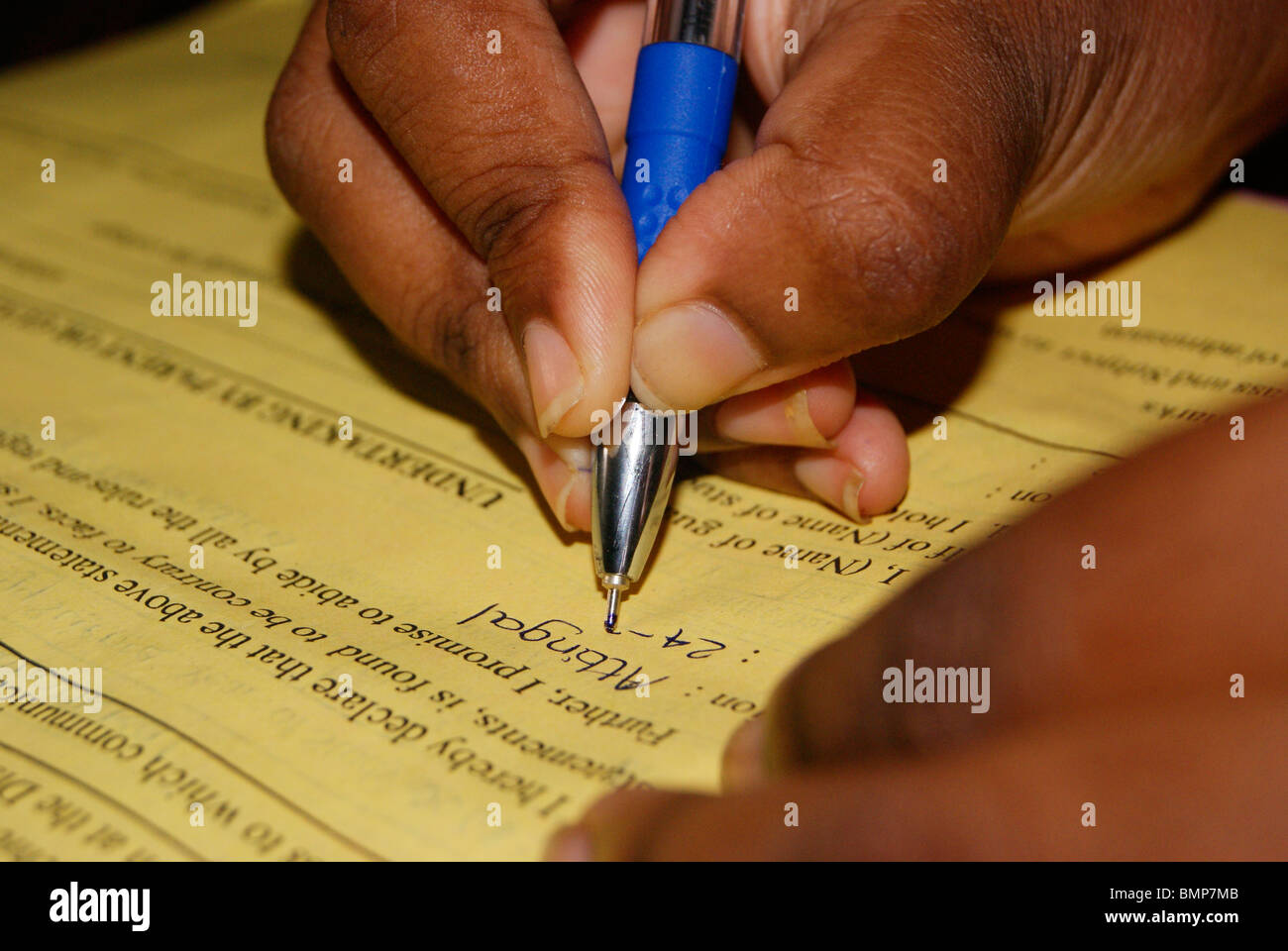 Exam and University Form Filling with right hand by a small girl with her blue ball point pen Stock Photo