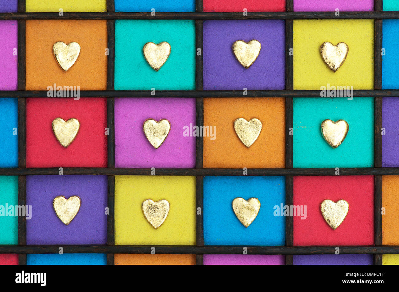 Multicoloured gold heart shape grid pattern in a wooden tray Stock Photo
