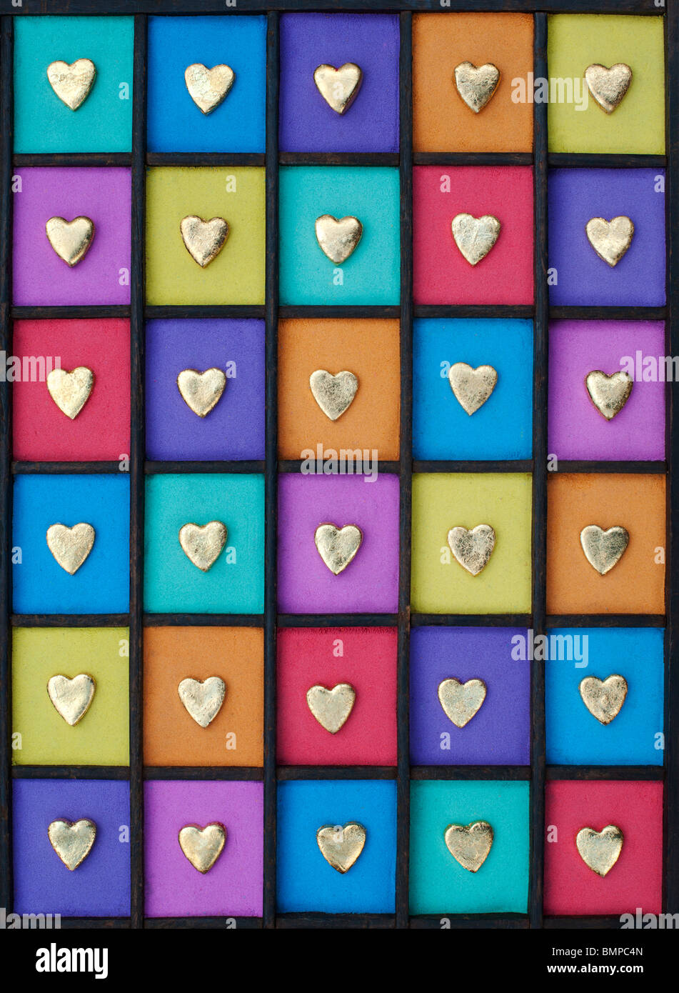 Multicoloured gold heart shape grid pattern in a wooden tray Stock Photo