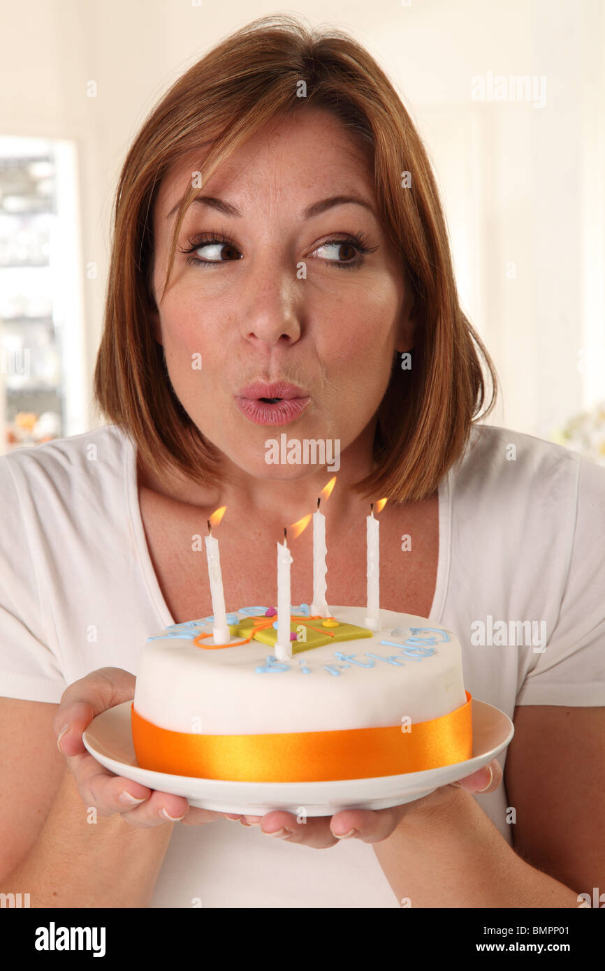 WOMAN BLOWING OUT CANDLES ON BIRTHDAY CAKE Stock Photo Alamy
