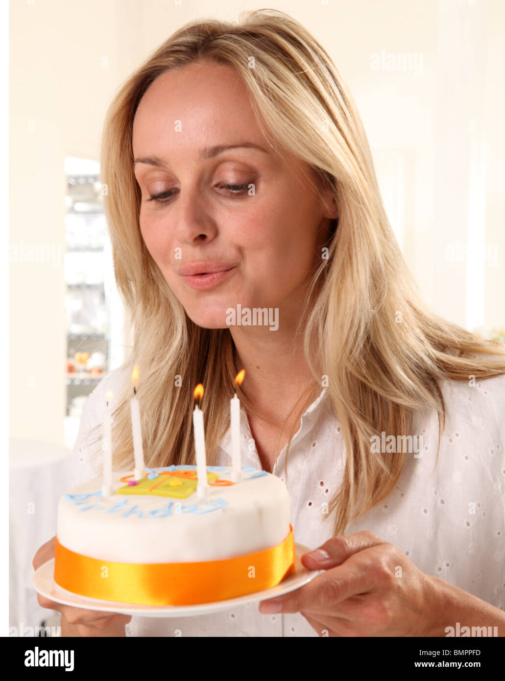 WOMAN BLOWING OUT CANDLES ON BIRTHDAY CAKE Stock Photo Alamy