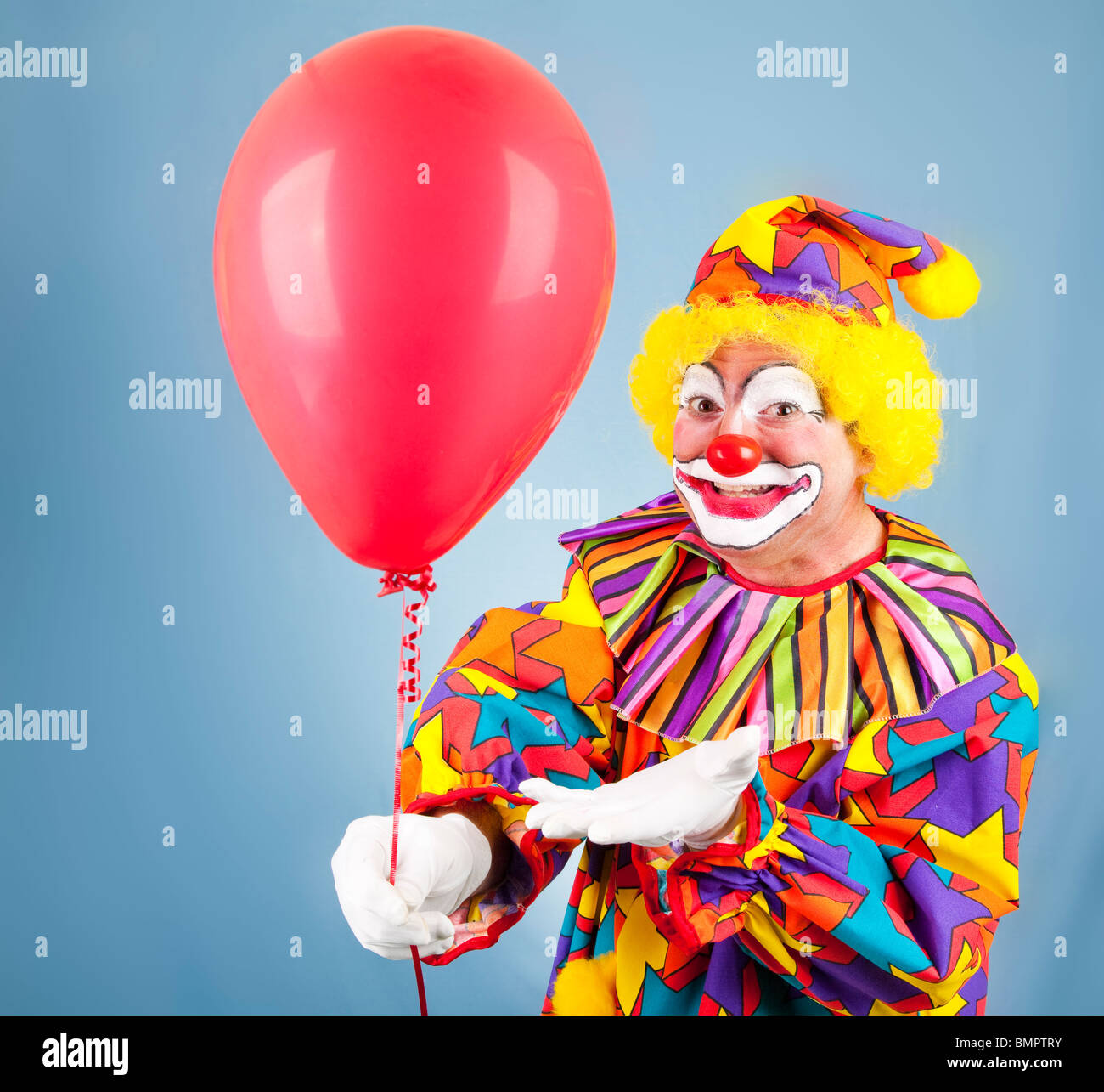 Friendly clown hands you a bright red balloon Stock Photo - Alamy