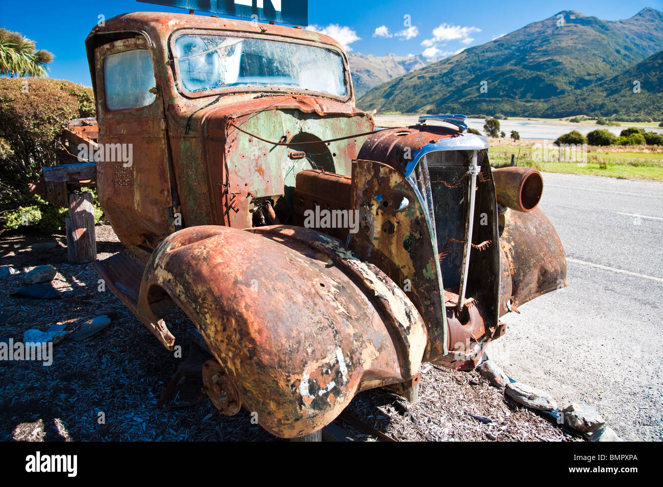 Old car wreck by road, West Coast, South Island, New Zealand Stock