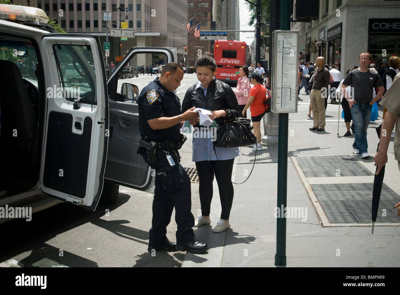 An NYPD police officer assists a woman in Lower Manhattan on Friday, June 11, 2010 (© Richard B. Levine) Stock Photo