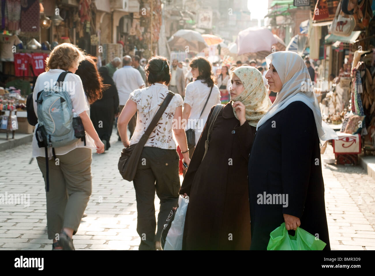 Culture contrast; Western tourists and local muslim arabic women in the multicultural Khan al Khalili market, the Islamic quarter, Cairo, Egypt Africa Stock Photo