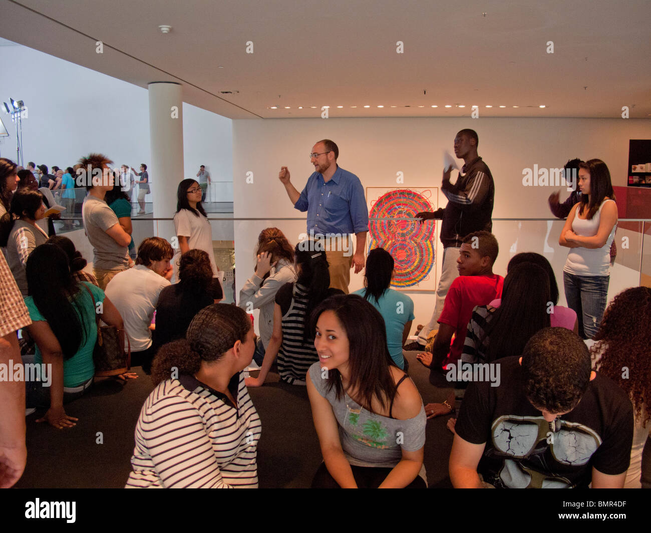 Explaining exhibits, a guide (center background) takes visitors through the Museum of Modern Art in New York City. Stock Photo