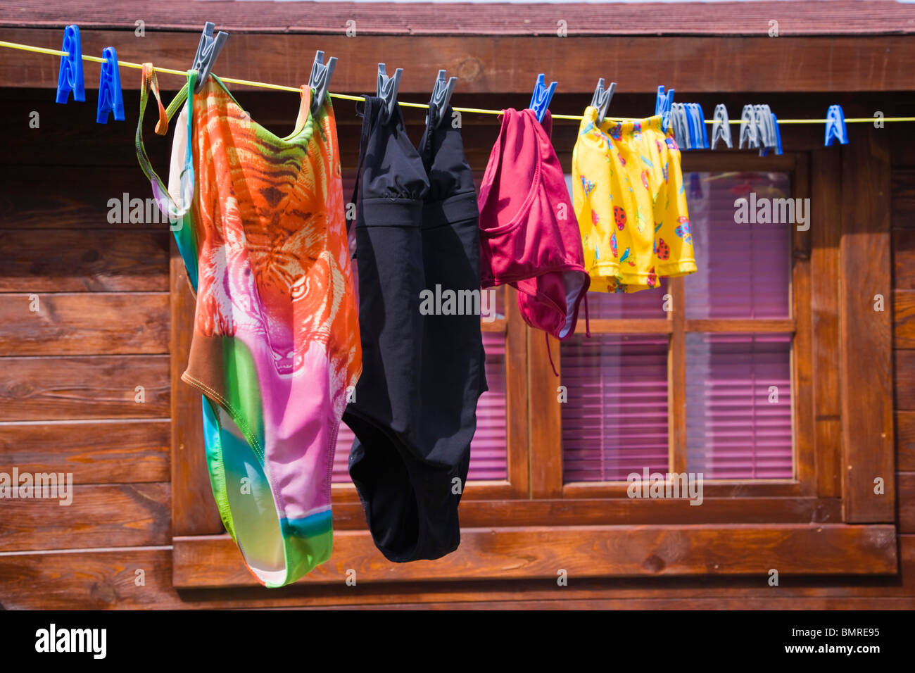 Washing line with drying swimming suits against log cabin Stock Photo
