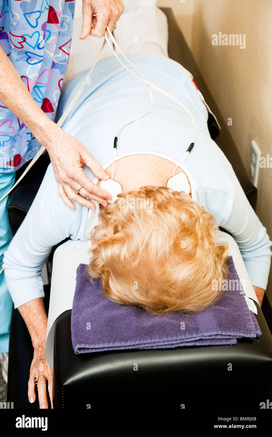 Electrical muscle stimulation in physical therapy. Therapist positioning  electrodes on a patient's knee Stock Photo - Alamy