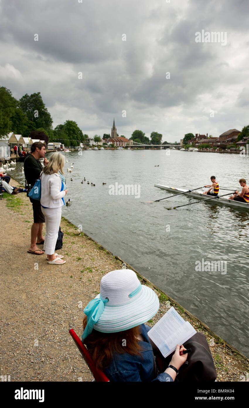 Lady wearing a fancy straw hat reading a book by the side of the River Thames during Marlow town festival annual regatta Stock Photo